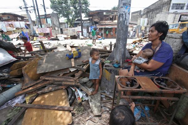 Wilma Francis, with her young children, sits on what is left of her store in Lorega-San Miguel market after it was demolished yesterday. (CDN PHOTO/ JUNJIE MENDOZA)