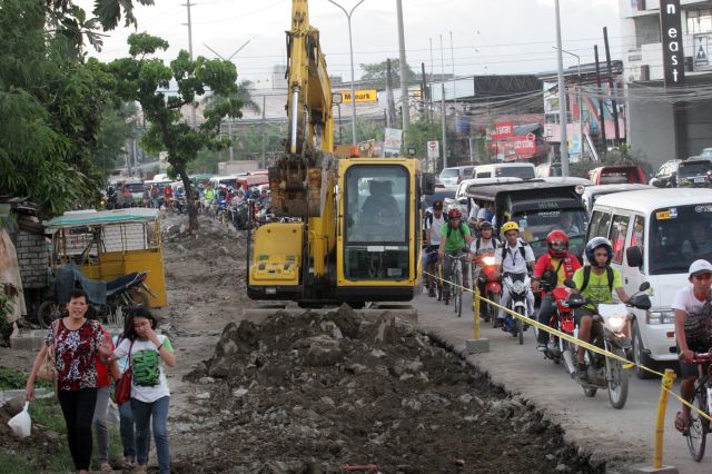 ROAD INCONVENIENCE. Pedestrians have to walk on the damaged road while a backhoe stands in the middle of a traffic jam along AC Cortes Ave., Mandaue City. (CDN PHOTO/JUNJIE MENDOZA)