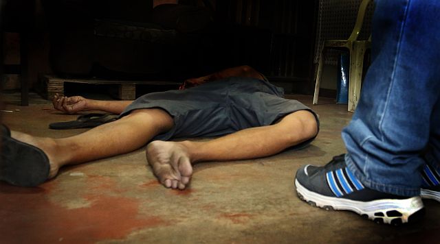 A Cebu City Police Office homicide investigator stands over the body of Alfredo Domingo, a suspected drug user, who was shot dead by an unknown assailant in Villagonzalo ll, Barangay Tejero, Cebu City on June 9. (CDN FILE PHOTOS)