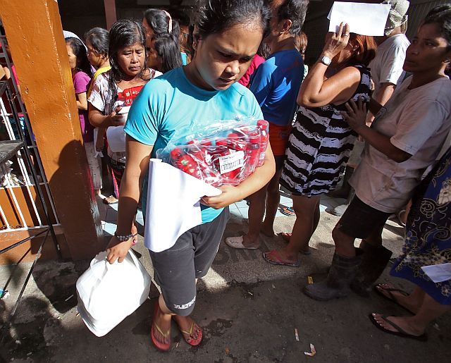 FOOD PACKS FOR BREAKFAST. Fire victims (above) queue to receive food packs for their breakfast given by the Cebu City government a few hours after the fire raged through six sitios in Barangay Duljo Fatima. (CDN PHOTOS/JUNJIE MENDOZA). 