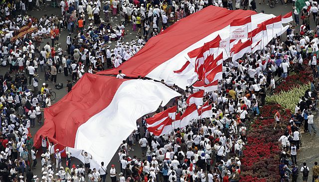 Indonesians display a large red and white national flag and smaller ones during a rally in Jakarta, Indonesia, Sunday, Dec. 4, 2016. Thousands of people staged the rally in attempt to demonstrate national unity as religious and racial tensions divide the world’s most populous Muslim nation. (AP PHOTO). 