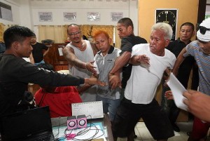 Cooler heads (top) try to restrain a relative of the Villamor couple who flared up on seeing the suspect  Jimson Roado at the Liloan police station. (CDN PHOTO/TONEE DESPOJO)
