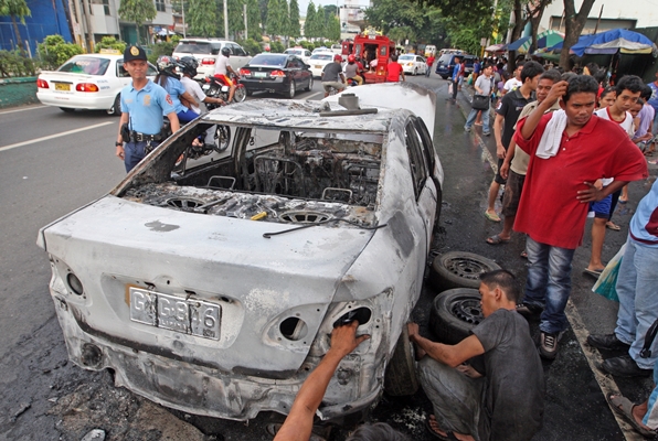 Taxi driver Jeniffer Superales (right) in shock after his taxi unit of RP Corominas caught fire along Bacalso Ave. (CDN PHOTO/TONEE DESPOJO)