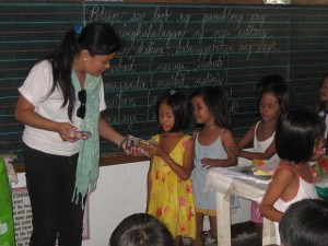 Compassionate. Mitzee Martin, a teacher by profession distributes pencils and crayons to schoolchildren who were among the beneficiaries of her group’s relief drive in nothern Cebu. (CONTRIBUTED PHOTO)