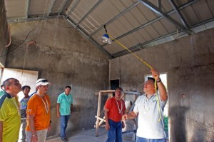 Cebu Gov Hilario Davide III (2nd from right) looks on as a representative from  Habitat for Humanity switches on a a solar-powered lamp in a housing unit for  Yolanda survivors in Sta. Fe town, Bantayan island.  (CDN PHOTO/TONEE DESPOJO)
