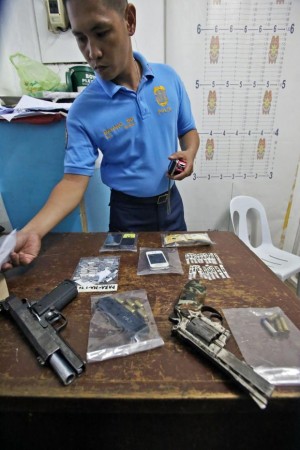A Moalboal police investigator inspects the items confiscated in Saturday’s drug raid that resulted in the death of police officers sitio Banilad, barangay Tomonoy, Moalboal, Cebu. (CDN PHOTO/ JUNJIE MENDOZA)