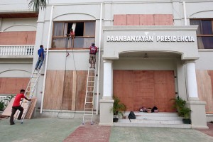 Workers used wooden boards to seal windows and doors of the Presidencia, the municipal hall of Daanbantayan town in northern Cebu to protect it from typhoon Ruby's howling winds. CDN PHOTO/TONEE E. DESPOJO