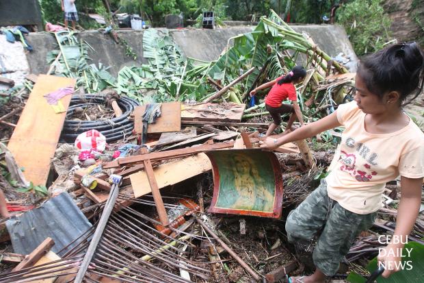 SALVAGING. A resident of sitio Riverside in barangay Poblacion, Boljoon town   picks up pieces of their house that tropical storm Queenie washed out last Thursday. (CDN PHOTO/ TONEE DESPOJO)