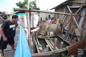A neighbor looks at the fenced hole, about six feet wide and 30 feet deep, in the backyard of Ernesto Ogabao, 46, in barangay Maslog, Danao City. What were they diging? Ogabo's body was recovered in the hole with two other relatives who were helping excavate it. A neighbor, Diomel Mayol 19, also died when he went down trying to rescue them last Friday, Dec. 26. (CDN PHOTO/ JUNJIE MENDOZA)