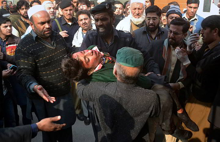 Hospital security guards carry a students injured in the shootout at a school under attacked by Taliban gunmen in Peshawar, Pakistan, Tuesday. Taliban gunmen stormed a military school in the northwestern Pakistani city, killing and wounding dozens, officials said, in the latest militant violence to hit the already troubled region. (AP)