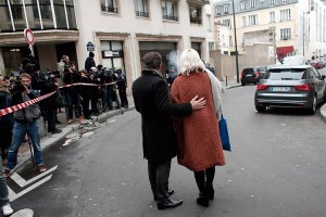 People stand outside the French satirical newspaper Charlie Hebdo's office after a shooting, in Paris, Wednesday, Jan. 7, 2015. Masked gunmen stormed the offices of a French satirical newspaper Wednesday, killing at least 11 people before escaping, police and a witness said. The weekly has previously drawn condemnation from Muslims. (AP Photo/Thibault Camus)
