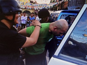 Shikeb Saddozai is whisked into a police car after his arrest in barangay Sambag Uno, Cebu City. (CONTRIBUTED PHOTO)