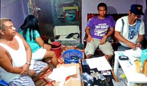 Marcial Inso (left) watches SPO1 Jeoffrey Diola examine packs of suspected shabu seized in the house of Jollybe Inso in a drug raid in barangay Suba, Cebu City. (CONTRIBUTED PHOTO)
