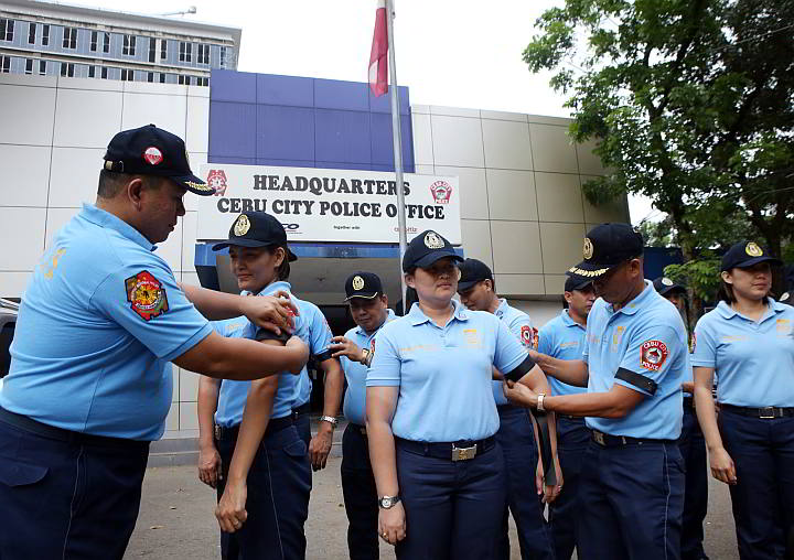 Supt. Romeo Santander, (left) chief of the City Intelligence Branch of the Cebu City Police Office, places black armbands on colleagues  to show their sympathy for the policemen killed in Maguindanao. (CDN PHOTO/LITO TECSON)