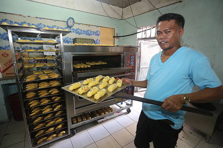 Inmate Lito Granada shows freshly baked  bread from the jail’s oven for sale later in a self-service cafe run by inmates. (CDN PHOTO/TONEE DESPOJO)