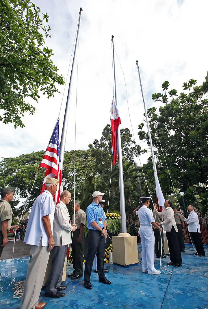 Talisay City Mayor Johny Delos Reyes raises the  Philippine Flag while US Consul John Domingo  (2nd from  left) and Retired Japanese Capt. Takeshi Ishida (far right) wait for their turn to raise the US and Japanese Flags in Poblacion, Talisay City. (CDN PHOTO/JUNJIE MENDOZA)