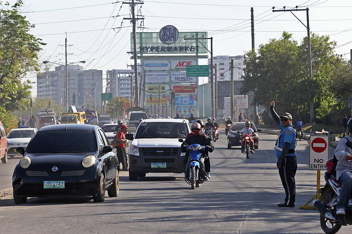 A traffic enforcer guides vehicles passing along M. Logarta Street during the enforcement of the  one-way traffic flow. (CDN PHOTO/ JUNJIE MENDOZA)