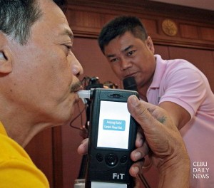 George Ancajas of dyDD Bantay Radyo blows through the  mouthpiece of a breath alcohol testing device used by LTO operations officer Joel Maloloy-on.  (CDN Photo/Junjie Mendoza)