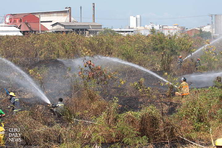 SRP GRASS FIRE Fire volunteers train their hoses on burning grass which caught fire towards noon last  Wednesday at the South Road Properties near the San Pedro Calungsod templete. (CDN PHOTO/JUNJIE MENDOZA)