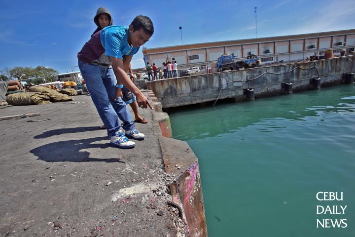 A bystander points to the concrete part of the pier which took the impact. (CDN PHOTO/ JUNJIE MENDOZA)