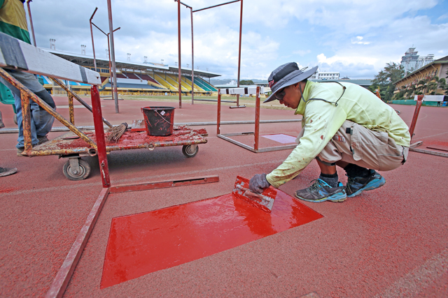 Malaysian national Steven Ong of Sports International Technology fixes a damaged portion of the rubberized oval track  of the Cebu City Sports Center. CDN PHOTO/JUNJIE MENDOZA