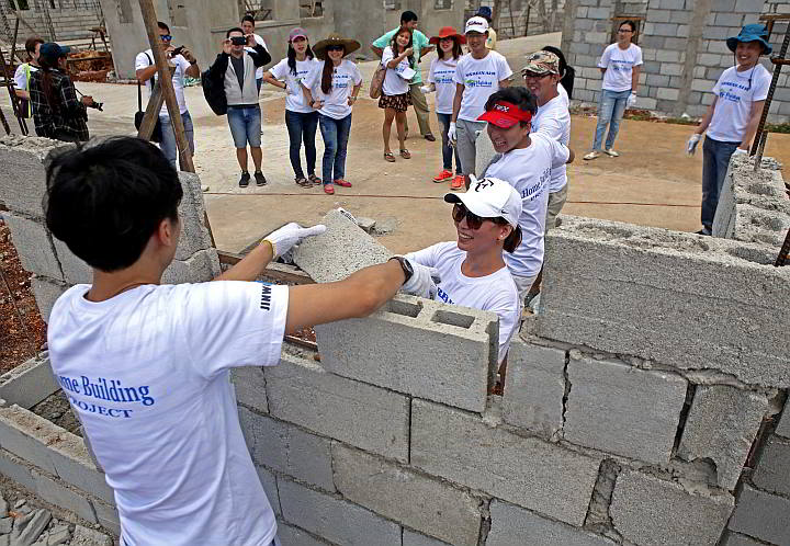 Arah Balbona (wearing a cap) of Korean Air helps build one of the houses they donated to Yolanda victims in barangay Paypay, Daanbantayan together with their employees.   (CDN PHOTO/LITO TECSON)