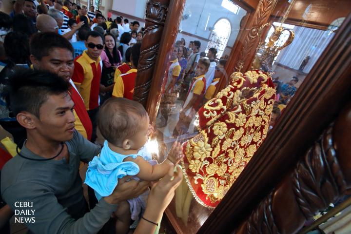 With his father lifting him up, a child touches the glass case containing the replica of the Senor Sto. Nino image in the Archdiocesan Shrine of San Nicolas de Tolentino in barangay San Nicolas. (CDN PHOTO/ JUNJIE MENDOZA)