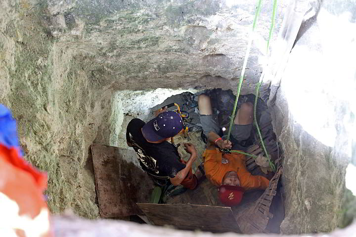 Barangay officials and curious onlookers watch as a man goes down a hole in barangay Apas (CDN PHOTO/ JUNJIE MENDOZA)