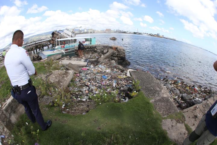 A security guard assigned at Shell island looks at urban garbage swept in by the waves in this January 2015 file photo. 