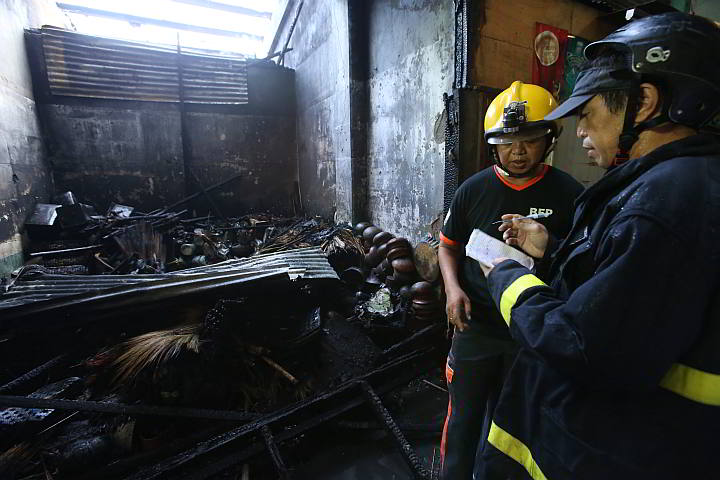 A Cebu City firemen check the damage caused by the fire in one of the stalls in Taboan Public market. (CDN PHOTO/ JUNJIE MENDOZA)