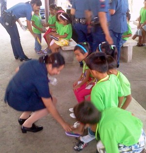 Cemetery kids receive new slippers from Lapu-Lapu City Police Community Relations personnel at the end of their month-long series of lectures on per sonality enhancement. (CDN PHOTO/NORMAN MENDOZA)