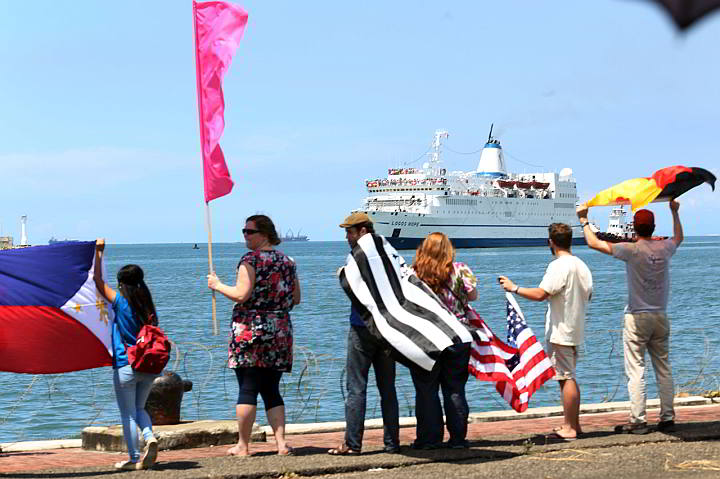 Student volunteers wave flags as MV Logos Hope approaches Cebu port. (CDN PHOTO/ JUNJIE MENDOZA)