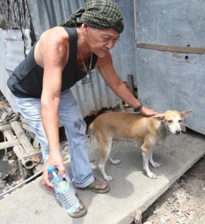 Carlos Paller pets the family dog Regine a day after she woke them up when their house caught on fire last Saturday. (CDN PHOTO/ JUNJIE MENDOZA)