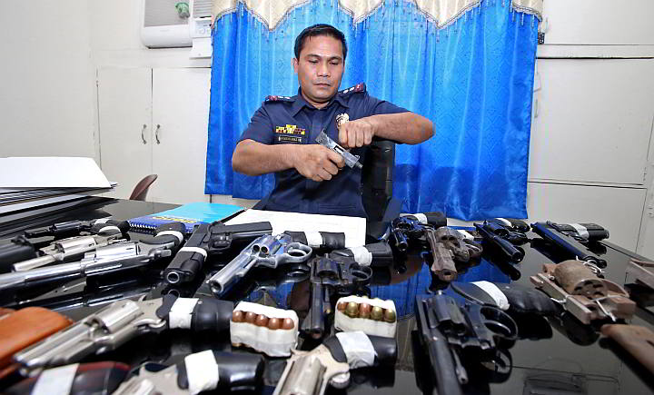 Supt. Fermin Armendarez, deputy chief of the Criminal Investigation and Detection Group (CIDG) 7, checks one of the firearms seized in their simultaneous raids in the different parts of Cebu over the weekend. (CDN PHOTO/JUNJIE MENDOZA)