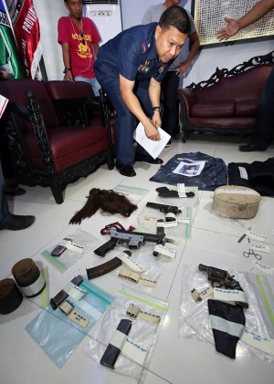 ‘TOOLS OF THE TRADE’. Chief Supt. Prudencio Bañas, Police Regional Office (PRO-7) chief, examines the assorted firearms, police uniform, bullet proof vest and some illegal drugs seized from the mountain hideout of murder suspect Ronjohn Labrador in Barili town, southwest Cebu. (CDN PHOTO/JUNJIE MENDOZA)