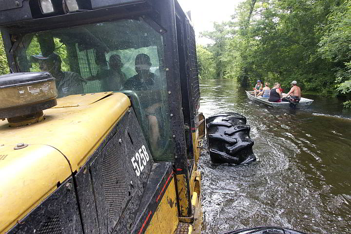 Trey Pike drives a logging skidder carrying residents of the flooded Knights Forest subdivision in Hardin, Texas. Pike used the vehicle to transport residents, as well as needed supplies, in and out of the flooded subdivision. (AP)