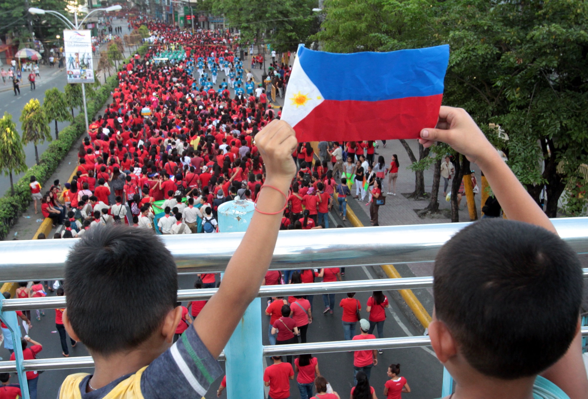 Young patriots hold aloft a Philippine Flag as they wacth from a skywalk the annual civic military parade for the 117th celebration of Independence Day. The parade started in front of Cebu Capitol and proceeded to Plaza Independencia.(CDN/JUNJIE MENDOZA)