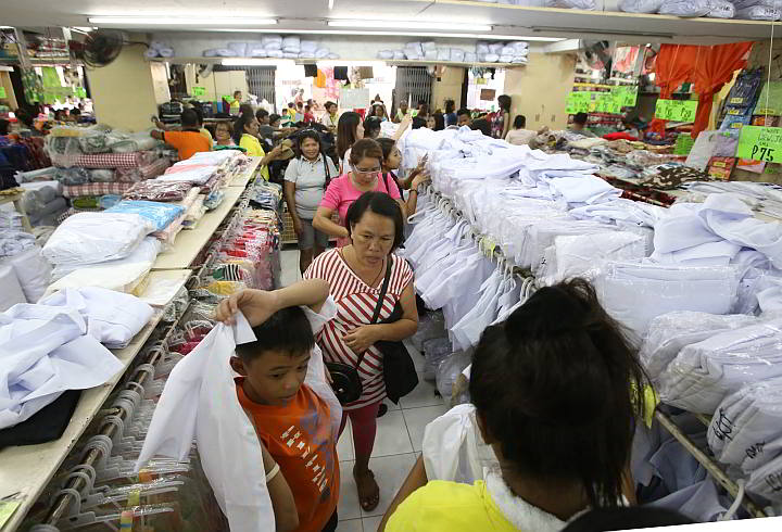 Parents bring their children to a store on Magallanes street to buy cheap school uniforms. Classes open today. (CDN PHOTO/JUNJIE MENDOZA)
