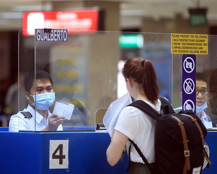 Immigration personnel at the Mactan-Cebu international Airport wear protective masks as they deal with arriving international travelers.