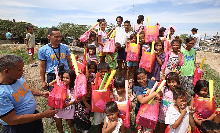 Street children from sitio Tanke II barangay Mambaling smile as they hold theri bags of new school supplies from the Cebu City police. 