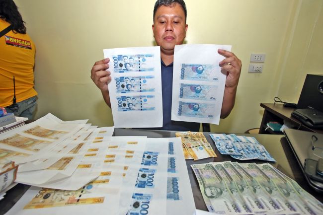 Supt. Romeo Santader, chief of the CIty Intelligence Branch of the Cebu City Police Office, shows the fake bills recovered from Dexter Ledesma and Dante Marticio (right photo), who were arrested last Monday night.(CDN PHOTO/JUNJIE MENDOZA)