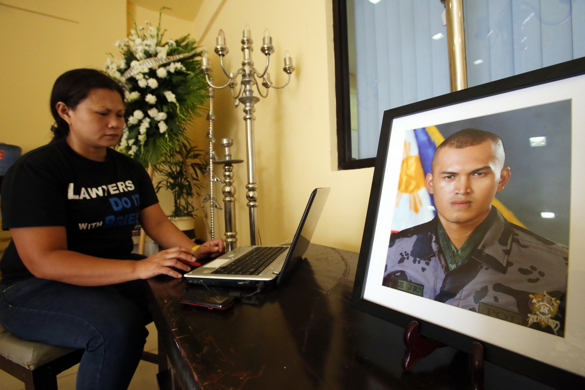 Aileen Ruiz communicates with some relatives using her laptop near the photo frame of her son P01 Christopher Ruiz Jr., who died in a police training camp in Sibonga town, cebu.(CDN/JUNJIE MENDOZA)
