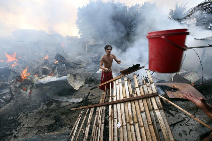 A house owner tries to catch a pail of water thrown to him by neighbors helping put out a Saturday afternoon fire in barangay Tabunok, Talisay City. (CDN PHOTO/ JUNJIE MENDOZA)