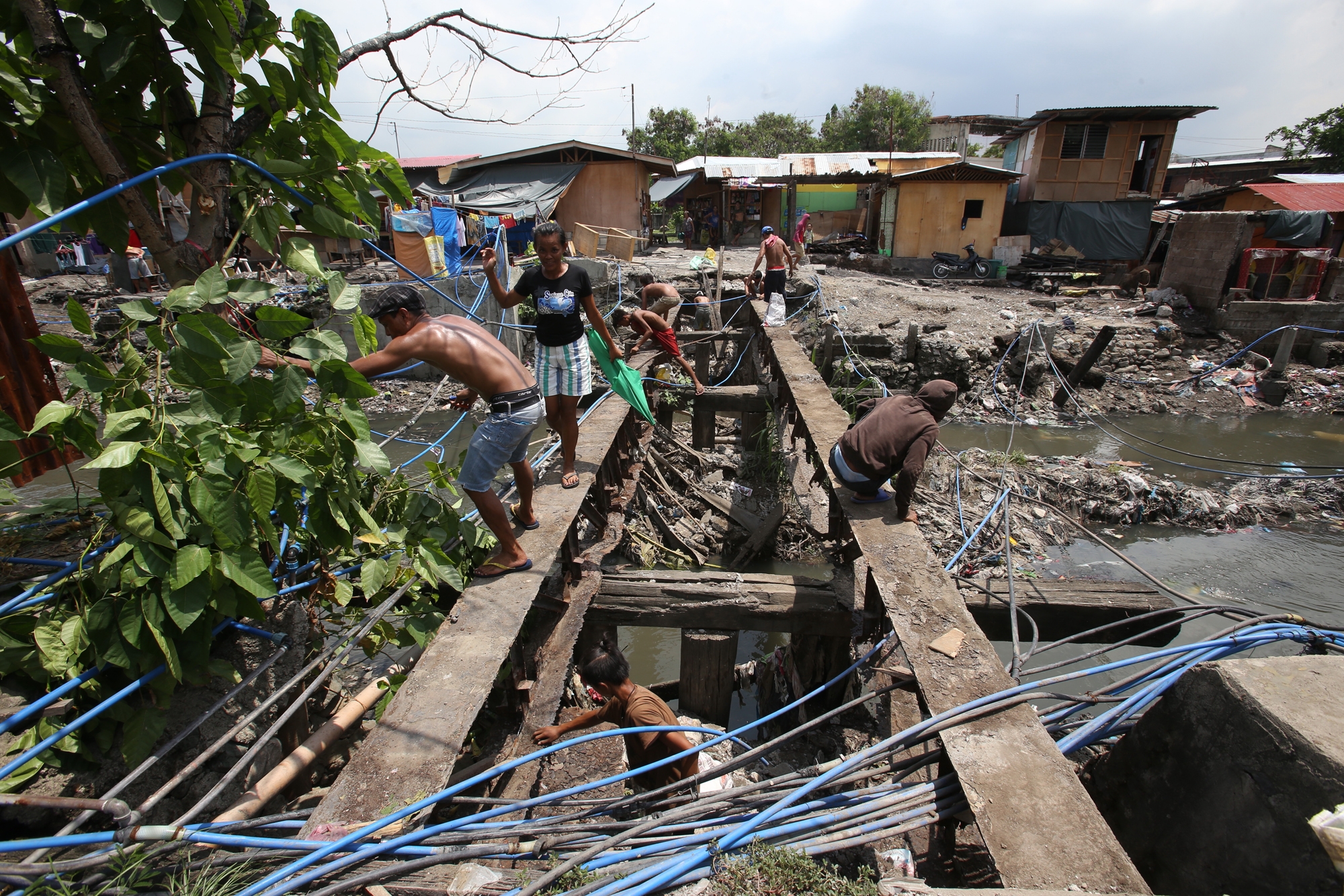 Residents voluntarily dismantle a wooden foot bridge over the Mahiga Creek connecting barangay Mabolo in Cebu City and barangay Subandaku in Mandaue City. At least 18 foot bridges are the subject of demolition.(CDN/JUNJIE MENDOZA)