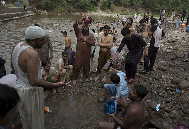 People cool themselves off at a stream in Islamabad, Pakistan as temperatures rose during Ramadan yesterday. /AP photo