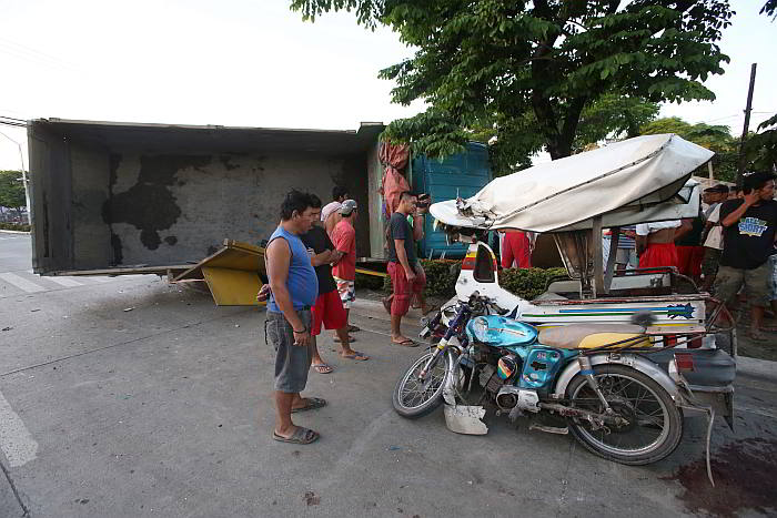 Bystanders look at the damaged tricycle and truck at the crossing of San Isidro, Talisay and SRP. (CDN PHOTO/ JUNJIE MENDOZA)