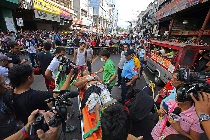 Gunshot victim Jaime Villaceren is brought on a gurney to a waiting ambulance by Basak Pardo Emergency Rescue workers  in Osmeña Boulevard, where a crowd gathers. (CDN PHOTO/ LITO TECSON)