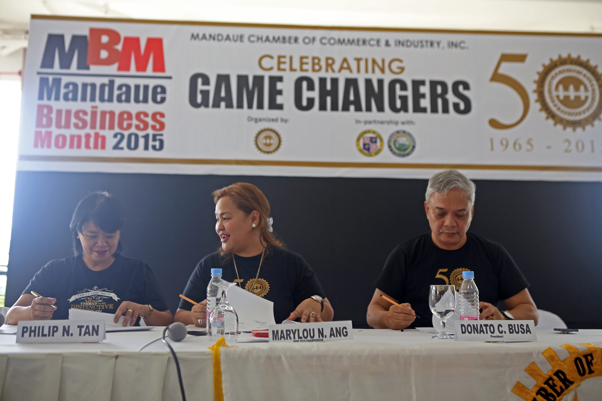 Marylou Ang (center), overall chairman of the Mandaue Business Month; Girlie Garces, San Miguel corporate communication officer, and Donato Busa, Mandaue Chamber of Commerce and Industry president, sign an agreement during last Saturday’s launching of the Mandaue Business Month. (CDN PHOTO/LITO TECSON)