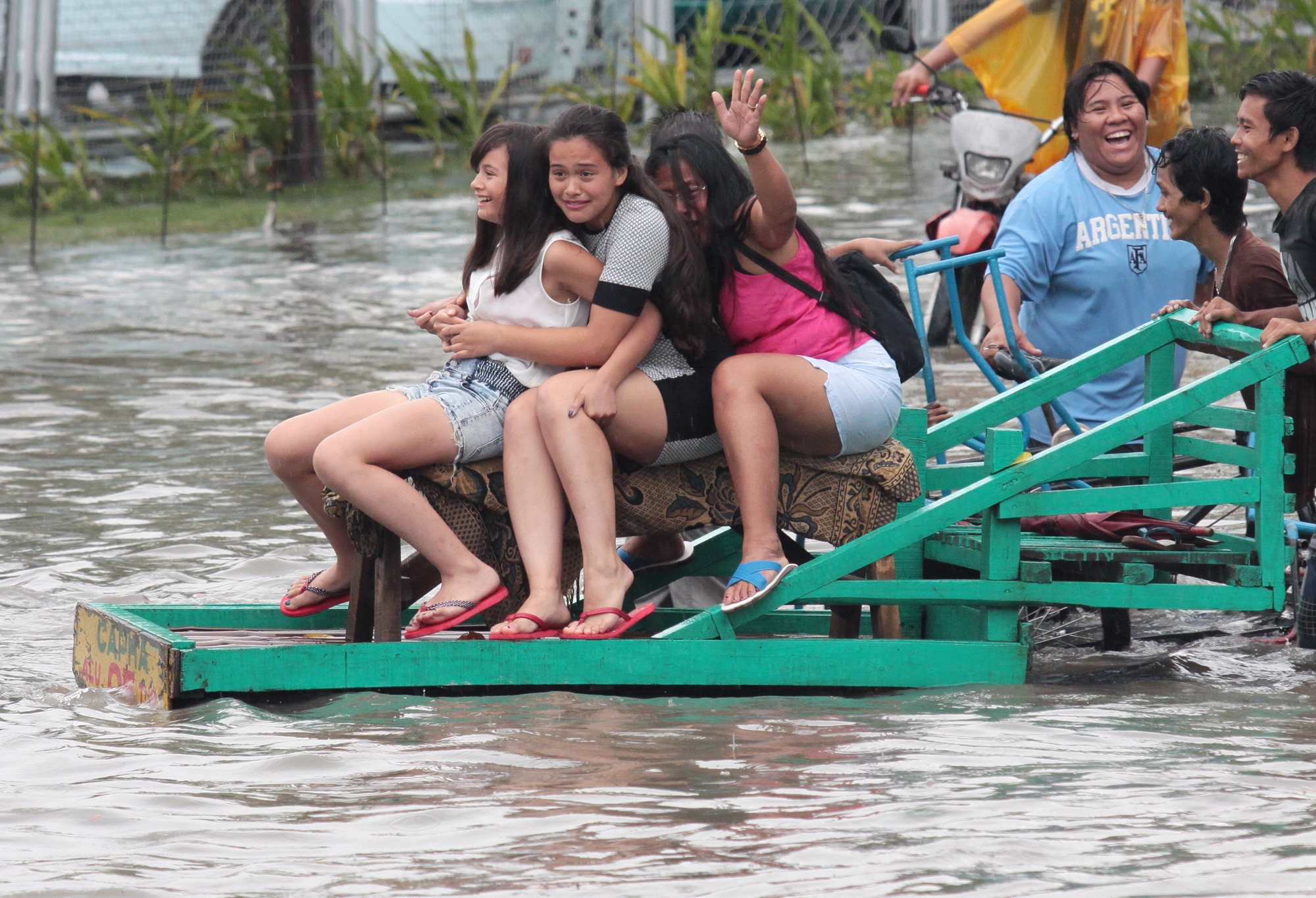 Some people board a wooden cart for P20 per person to cross over a knee deep flood water at Kaohsiung street North Reclamation Area Cebu City cuase by a heavy rain.(CDN PHOTO/JUNJIE MENDOZA)