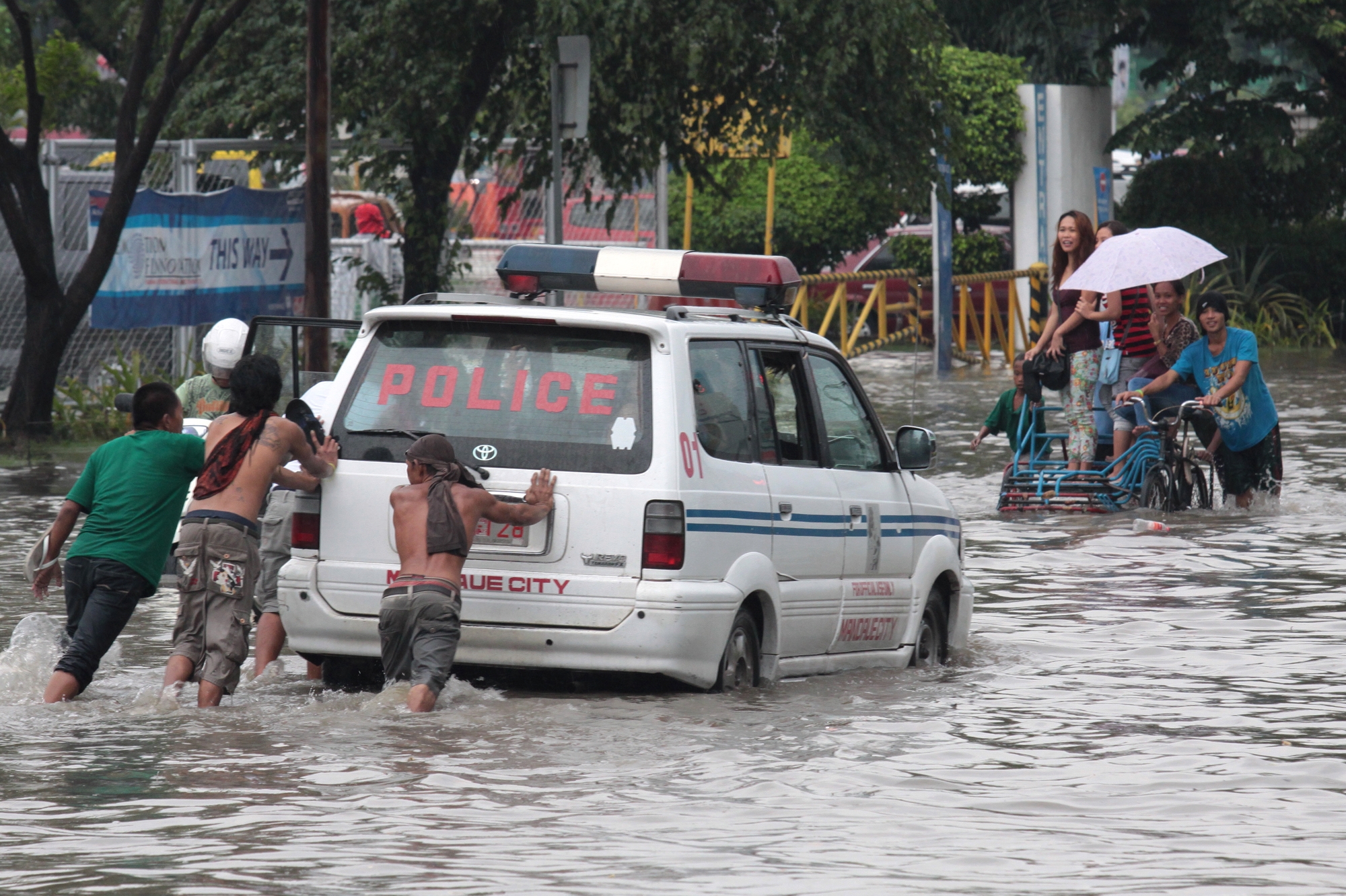 A patrol car of Mandaue City Police is being push while some people board a trisikad for P20 per person to cross over a knee deep flood water at Kaohsiung street North Reclamation Area Cebu City cuase by a heavy rain.(CDN PHOTO/JUNJIE MENDOZA)